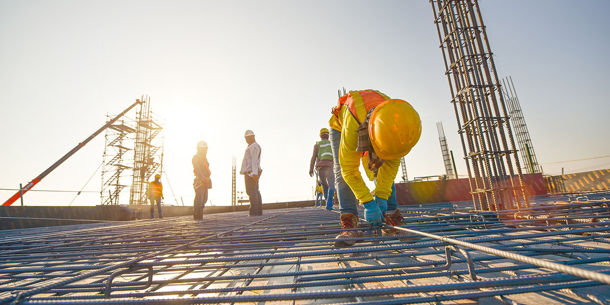 Comparison Of NVQ Levels In Construction — An NVQ assessor observing and guiding a construction worker during a hands-on sk